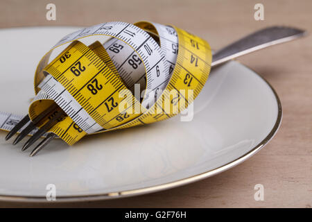 Forcella con nastro di misurazione come un simbolo della dieta rigorosa e la riduzione di peso Foto Stock