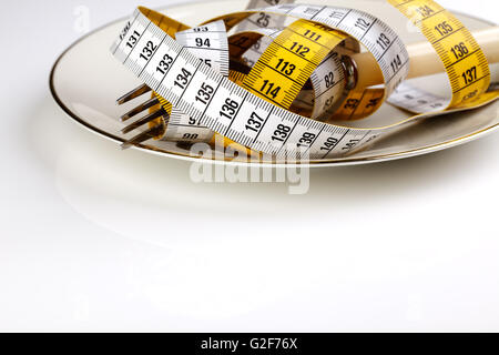 Forcella con nastro di misurazione come un simbolo della dieta rigorosa e la riduzione di peso Foto Stock