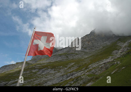 Bandiera svizzera svolazzanti sul vento in alta montagna vicino a Grindelwald nelle Alpi della Svizzera. Foto Stock