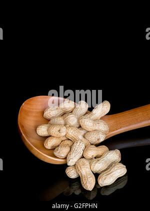 I dadi di scimmia, arachidi con cucchiaio su nero. Con copia spazio. Foto Stock