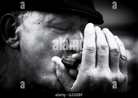 Ritratto di un maschio di blues harmonica player con gli occhi chiusi e un cappuccio in bianco e nero Foto Stock