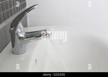 Bagno rubinetto di argento e di avere acqua che scorre nel concetto di risparmio idrico. Foto Stock