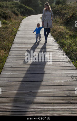 Donna e bambino tenendo le mani mentre passeggiate sul lungomare Foto Stock