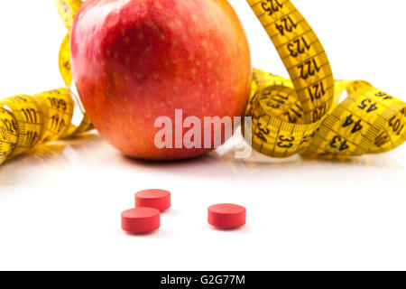Apple rosso giallo con nastro di misurazione e le pillole di rosso con la riflessione isolata su sfondo bianco Foto Stock