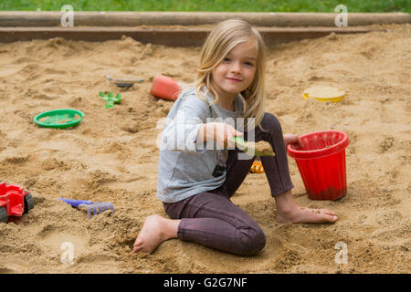 Bambina giocare Sandbox Parco giochi Digging sabbia Shovel costruzione  sabbia Figura giorno estivo. Caucasica femmina Bambini 5 anni divertirsi all 'aperto Foto stock - Alamy