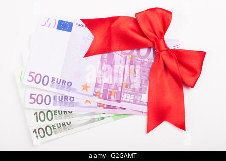 Sacco di banconote in euro battuta come un dono con nastro rosso isolato su sfondo bianco Foto Stock