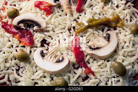 Pizza cruda rendendo closeup verde con olive e peperoni e formaggio Foto Stock