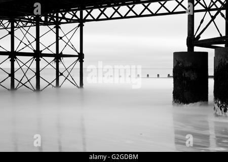 Struttura sotto Cromer Pier, pennelli, e le onde si fonde con la nebbia a Cromer Beach in Norfolk England Regno Unito Foto Stock