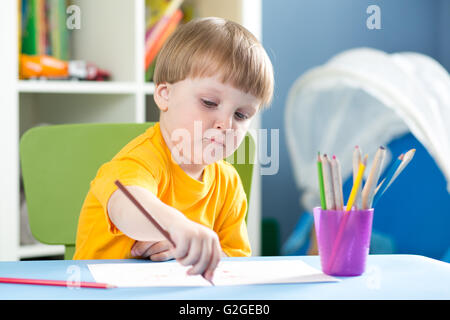 Carino piccolo ragazzo è un disegno con matite di colore in vivaio Foto Stock