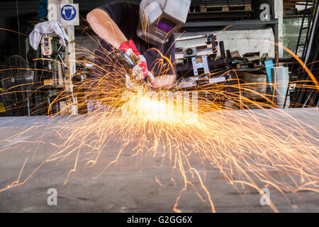 Lavoratore di metallo di macinazione in un workshop con scintille battenti Foto Stock