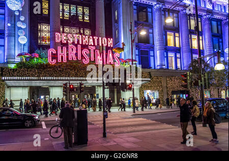 Cartello al neon 'Demination Christmas' sopra l'entrata principale del grande magazzino Selfridges su Oxford St di Londra, occupato da amanti dello shopping natalizio, Londra Foto Stock