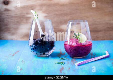 In casa ribes dessert, smoothie e organici locali congelate di ribes nero in un vetro di un blu in legno rustico Foto Stock