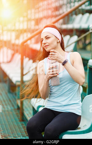 Giovane donna sportiva acqua potabile dopo il jogging. Bellezza ragazza europea riposo dopo l'esecuzione Foto Stock