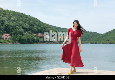 Moda donna in piedi di fronte ad un lago da soli Foto Stock