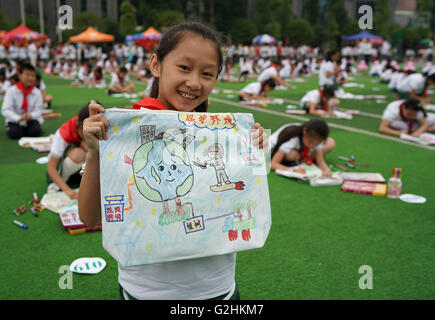 Chongqing. 31 Maggio, 2016. Un primario studente mostra la sua arte opere su un ambiente sacco durante un evento di pittura per celebrare la Giornata dei bambini e promuovere la consapevolezza della protezione ambientale nel sud-ovest della Cina della Municipalità di Chongqing, 31 maggio 2016. © Chen Cheng/Xinhua/Alamy Live News Foto Stock