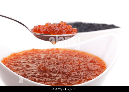 Rosso e Nero Perle di caviale in bianco ciotole e cucchiai d'argento isolato su sfondo bianco Foto Stock