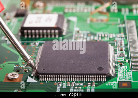 La misura di micro chip con la sonda rossa sulla scheda di circuiti verde Foto Stock
