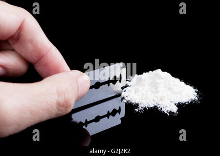 Una lama di rasoio closeup con whit della polvere del farmaco su sfondo nero con la riflessione Foto Stock