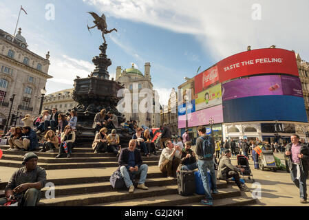 La Gente seduta sul Shaftesbury Memorial fontana con il dio greco Anteros o Eros a Londra, Piccadilly Circus Foto Stock