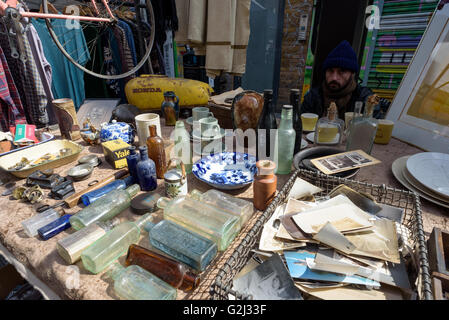 Cappello uomo vendita di bric-a-brac e antichi junk al suo mercato negozio di stallo su Brick Lane London Foto Stock