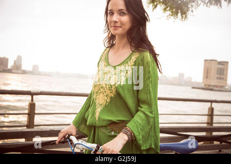 Ritratto di donna sorridente in bicicletta vicino al fiume, New York City, Stati Uniti d'America Foto Stock