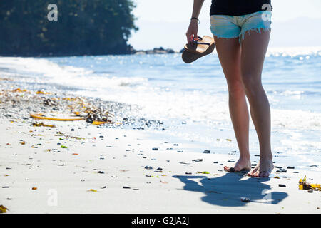 Una giovane donna si erge a piedi nudi sulla sabbia in spiaggia francese Parco Provinciale. Isola di Vancouver, BC, Canada. Foto Stock