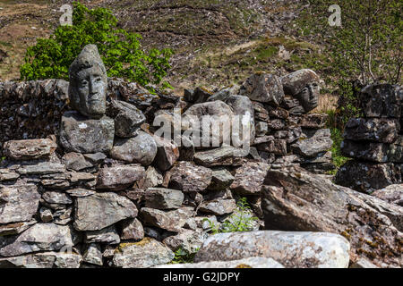 Volti scolpiti nella pietra sul muro di pietra nei pressi di Murray è un monumento, Galloway Forest Park, Scozia Foto Stock