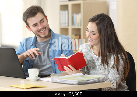 Due imprenditori lavorando e prendendo appunti insieme nella tabella di un piccolo ufficio Foto Stock