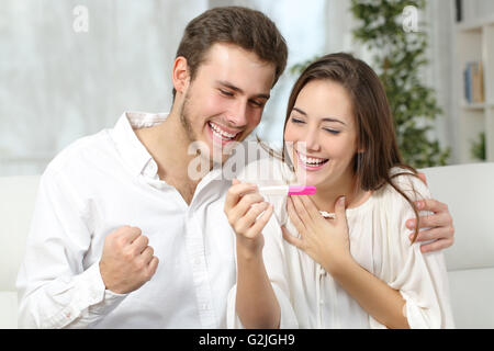 Felice coppia eccitate rendendo positivo al test di gravidanza e di celebrare la Foto Stock