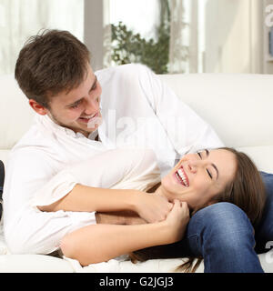 Gioiosa giovane o matrimonio scherzi e ridere insieme in un lettino a casa Foto Stock