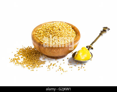Semi di senapa nella ciotola di legno con la salsa di senape in un cucchiaio isolato Foto Stock