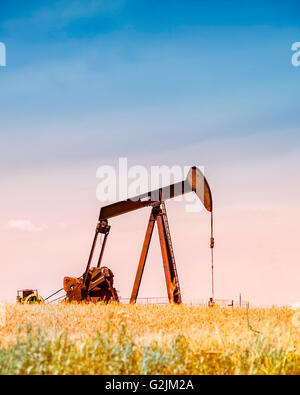 Un pumpjack pompa olio nel mezzo di un maturo campo di grano pronto per la mietitura in Oklahoma, Stati Uniti d'America.filtro applicato. Foto Stock