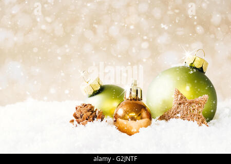 Un cono di fuoco e tre palle di Natale sulla neve con un tenue beige bokeh di fondo e la caduta di neve. Foto Stock