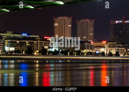 Vista notturna dalla riva del Danubio sul nuovo lusso parte del capitale slovacca - Bratislava. Linea di luci di passaggio di un battello. Foto Stock