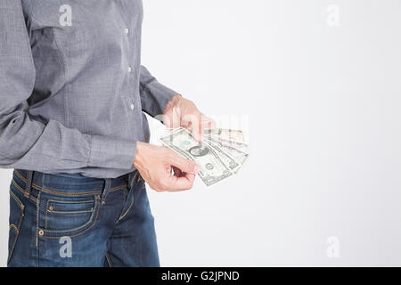 Donna blu jeans pantaloni e camicia grigia la valuta di conteggio denaro contante uno cinque dieci e venti banconote di dollari nelle sue mani isol Foto Stock
