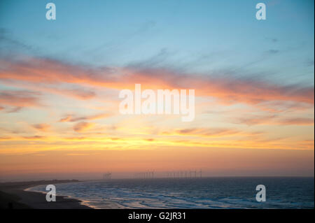 Le turbine eoliche a redcar spiaggia verde di produzione di energia rinnovabile nel mare al tramonto Foto Stock