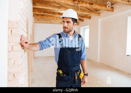 Giovani pensieroso builder pensando a qualcosa in ambienti interni Foto Stock