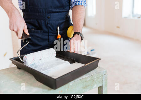 Close-up di le Mans mani con rullo di vernice durante il lavoro in ambienti interni Foto Stock