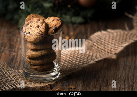 Freschi di forno biscotti con scaglie di cioccolato in un bicchiere su una tavola in legno rustico. Foto Stock