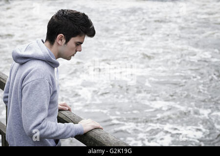 Premuto Giovane contemplando il suicidio sul ponte sul fiume Foto Stock