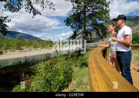 Coppia giovane savours vista fiume Similkameen mentre il campionamento vino dal frutto proibito cantina nei pressi di Cawston nella regione Similkameen Foto Stock