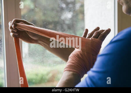 Uomo a mettere su una benda sulla sua mano prima di un allenamento di inscatolamento Foto Stock