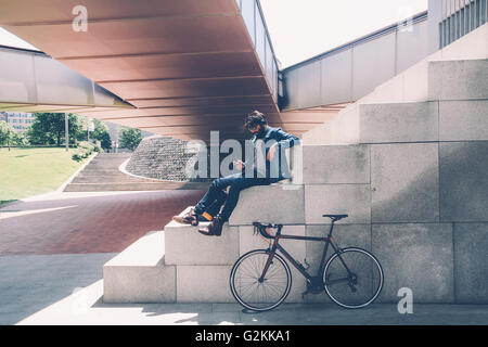 Spagna, Bilbao, l uomo con lo smartphone e cuffie, ciclo di corse Foto Stock