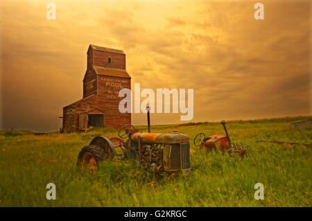 Elevatori della granella e i vecchi trattori in città fantasma Bents Saskatchewan Canada Foto Stock