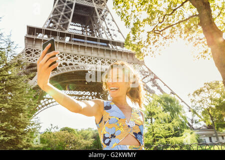 Parigi, Donna facendo un selfie con la Torre Eiffel sullo sfondo Foto Stock