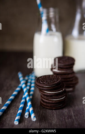 Due pile di Oreo cookie con cannucce a strisce e due bottiglie di latte Foto Stock