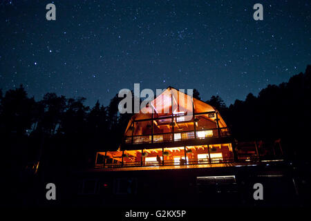 Cielo stellato sopra illuminato cabina di montagna Foto Stock