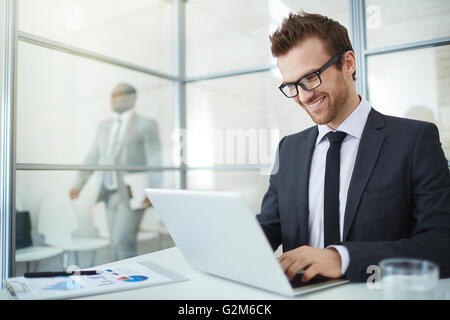 Giovane uomo nel convenzionale digitando in office Foto Stock