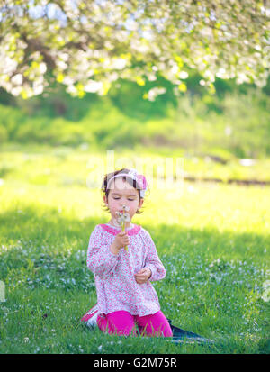 Bambino felice soffiando tarassaco all'aperto nel parco di primavera Foto Stock