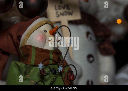 Decorazione per albero di natale di un pupazzo di neve indossando un cappello di vacanza, un cappotto e sciarpa e un segno in background che legge, io amo la neve. Foto Stock